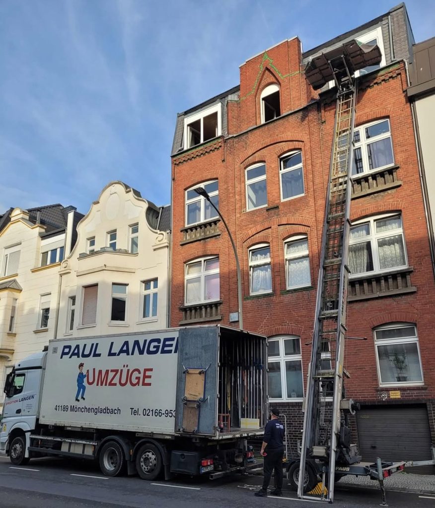 Umzugswagen von Paul Langen vor mehrstöckigen Wohnhäusern mit Möbellift für Privatumzug
